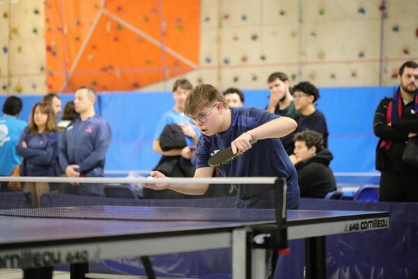 Un jeune du club au service, sous le regard des spectateurs