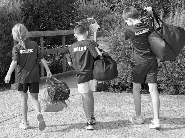 Trois jeunes du club, sac de sport &agrave; la main, sur le chemin du stage